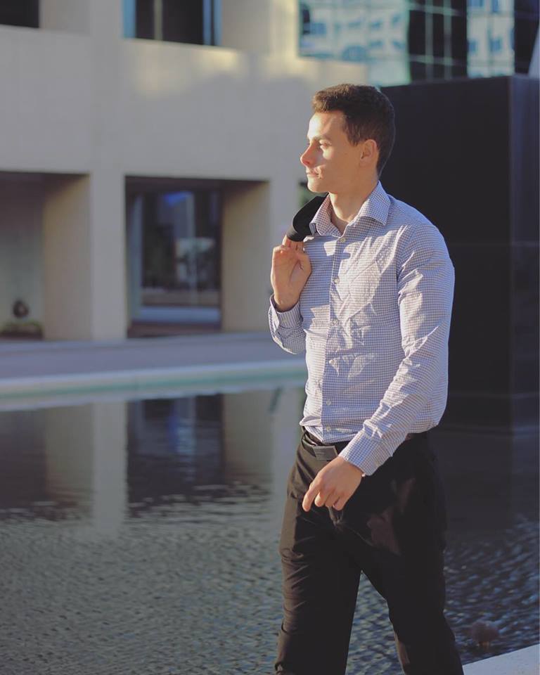 Lifestyle branding portrait of a man walking past a modern building with a reflecting pool