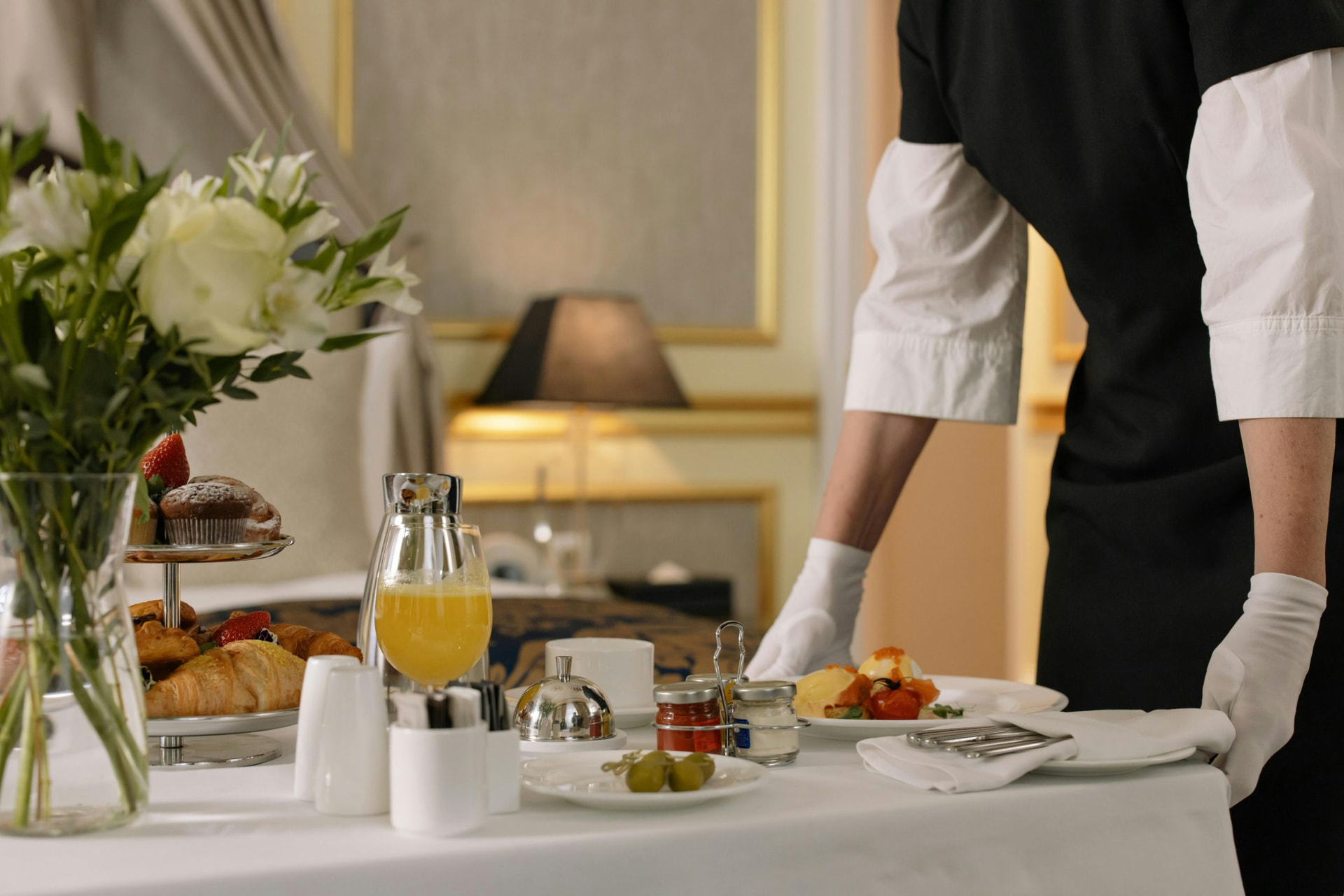 Hospitality professional setting a breakfast table in an elegant guest room