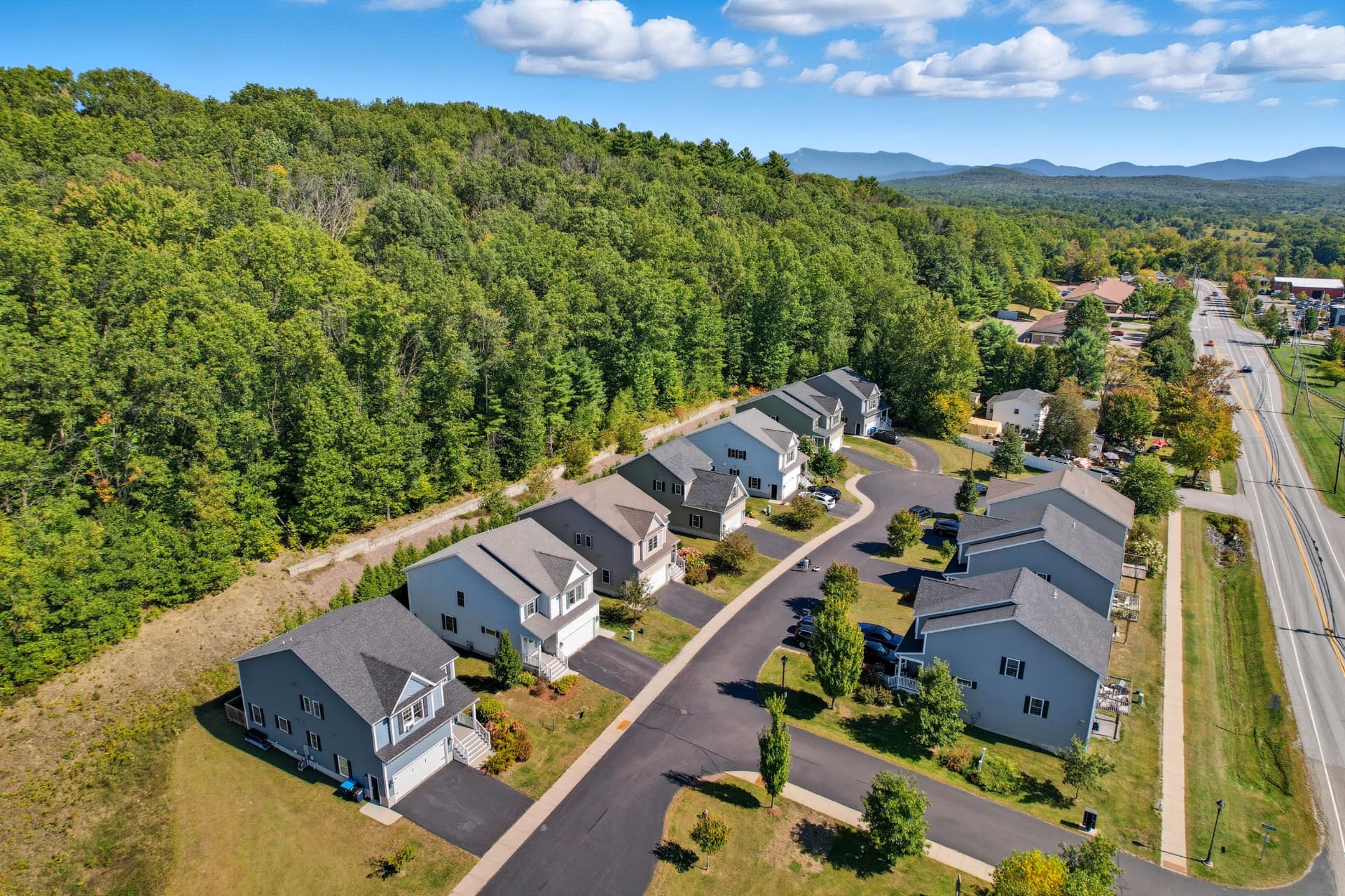 Aerial over a new home development with forested hillside and distant mountains