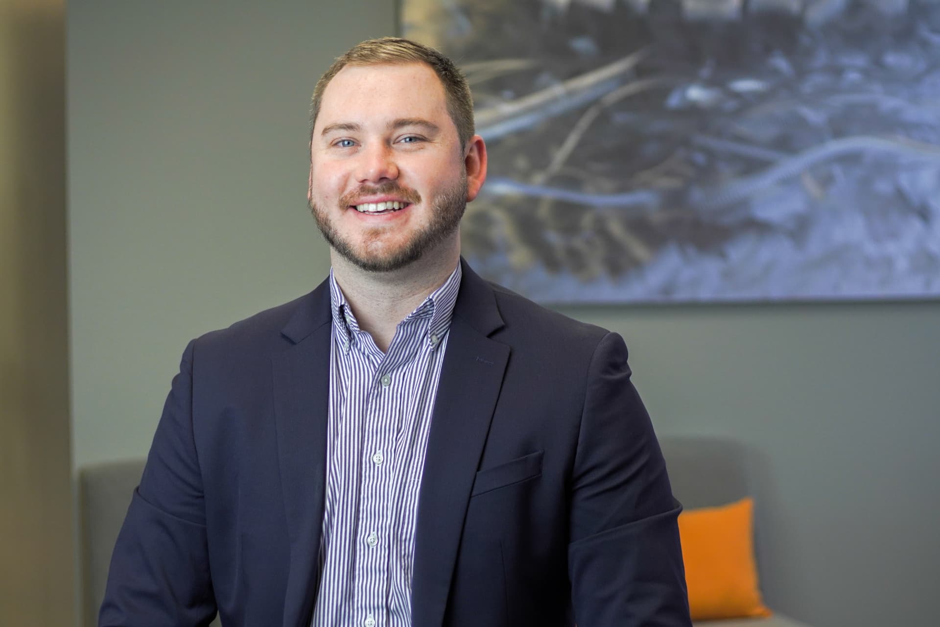 Professional office headshot of a smiling man in a navy blazer