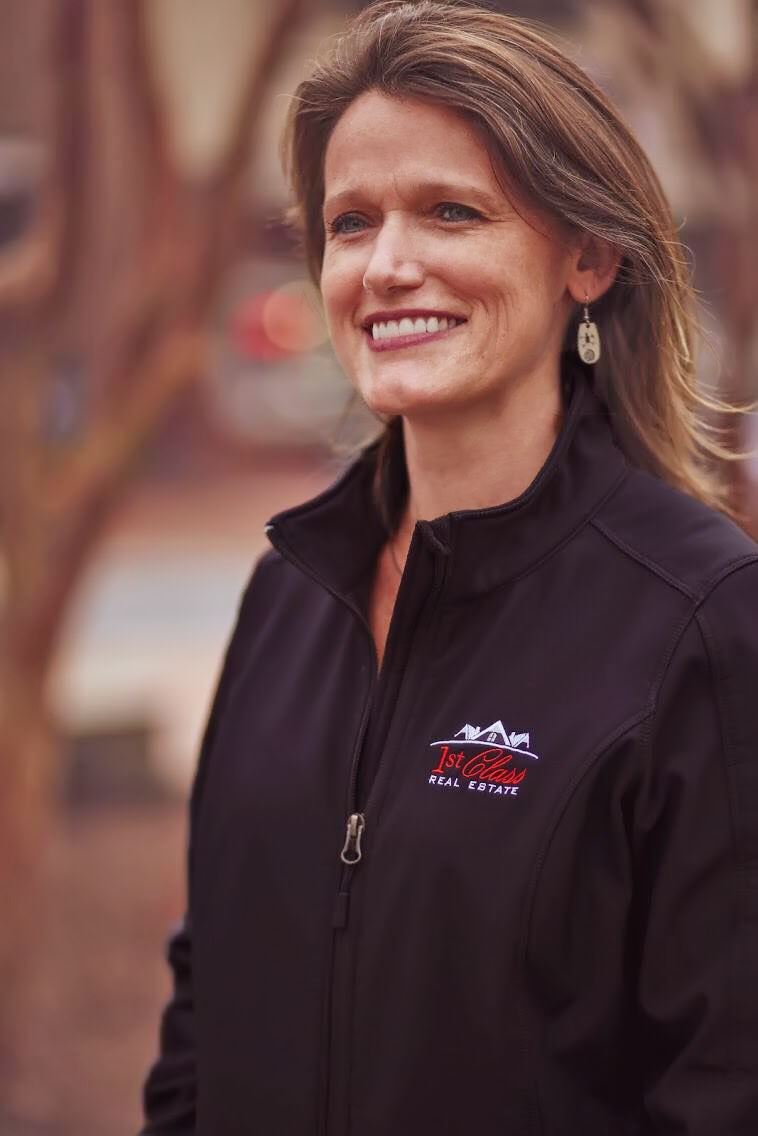 Lifestyle portrait of a smiling real estate professional in a branded jacket outdoors