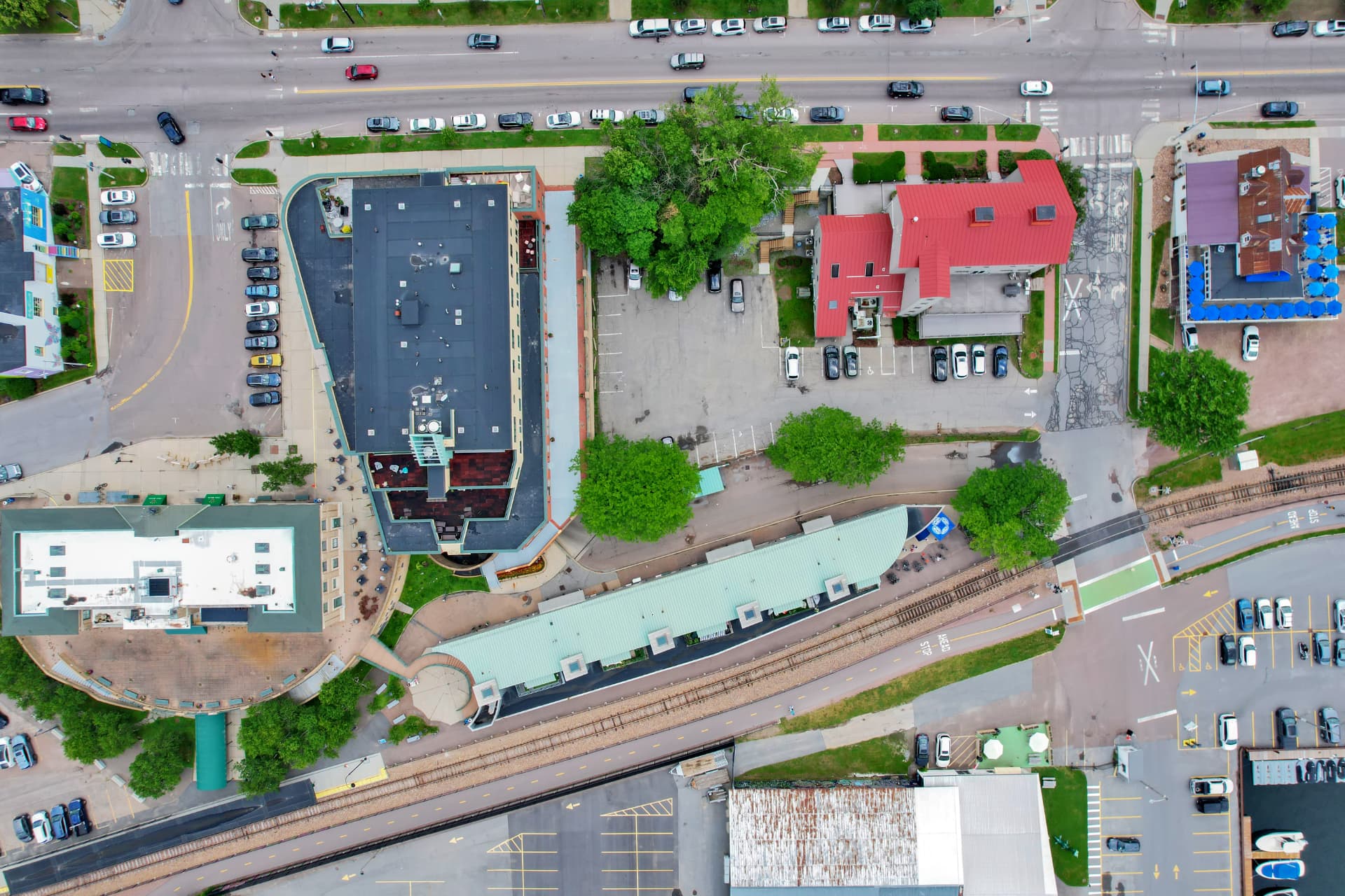 Top-down aerial view of downtown commercial blocks, parking, and rail line