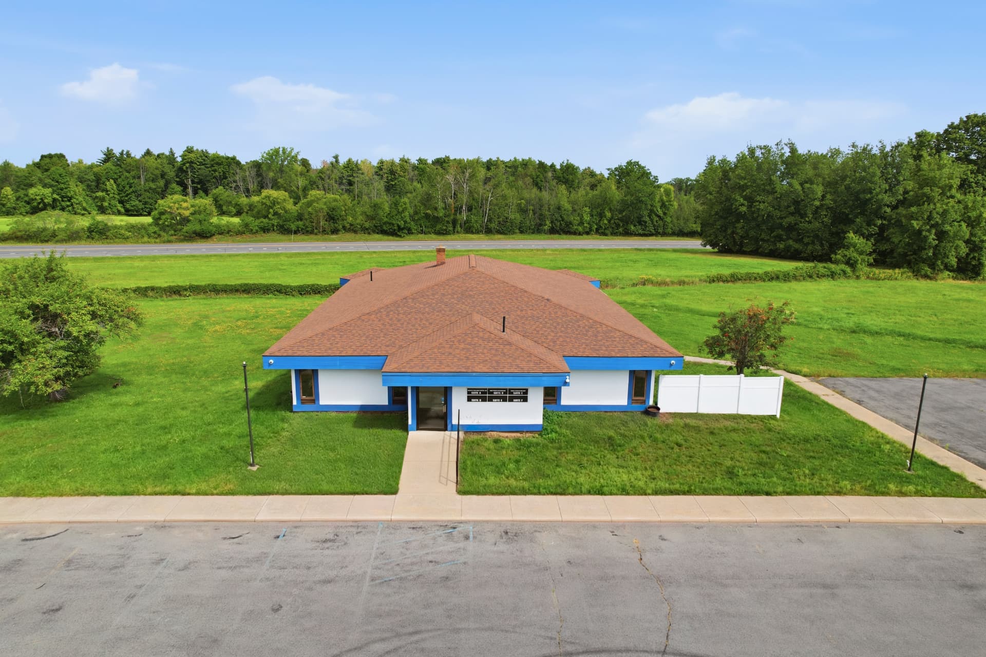 Aerial view of a single-story blue and white office building with surrounding green space