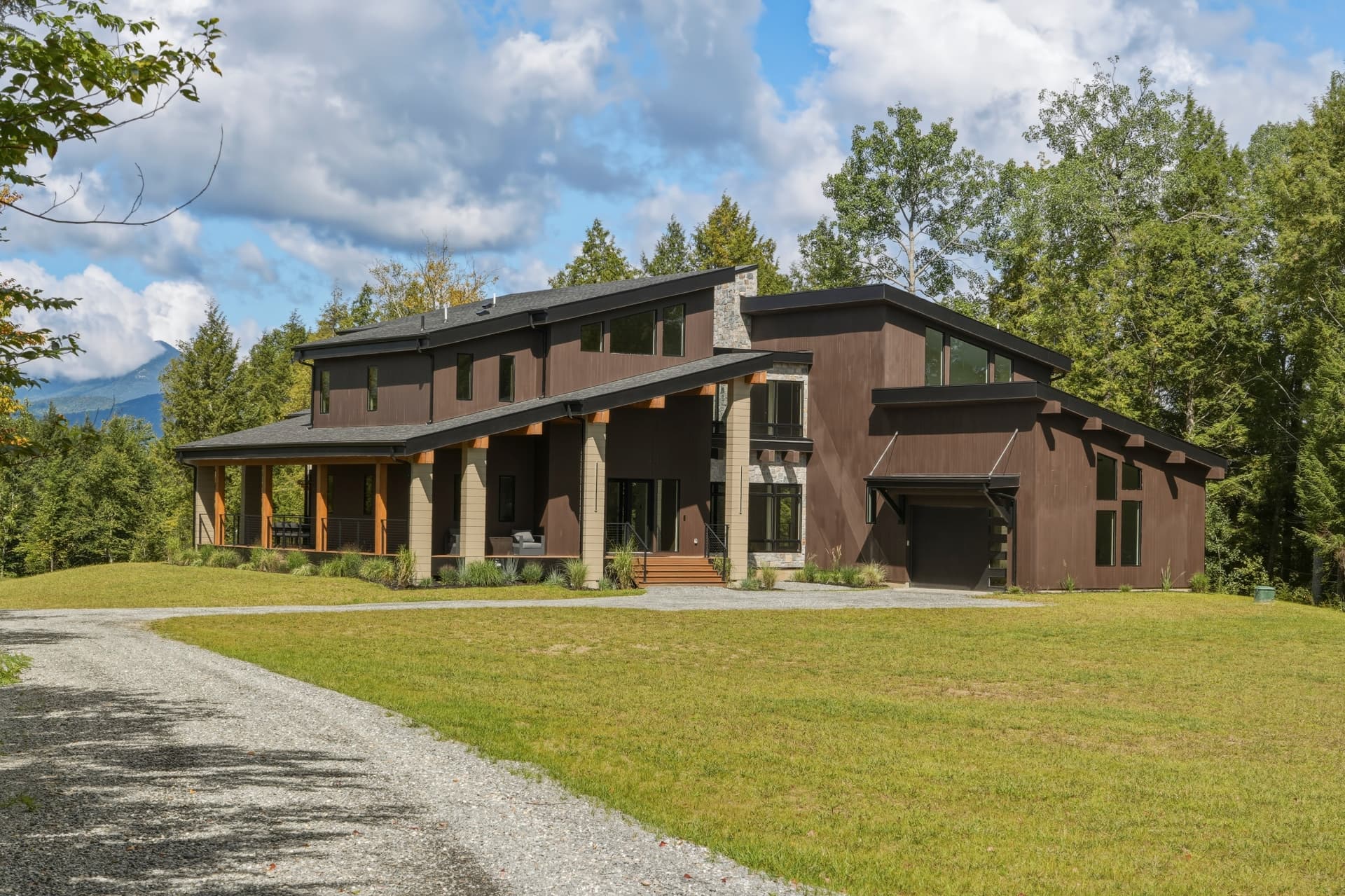 Front view of a modern brown commercial building with stone chimney and gravel drive