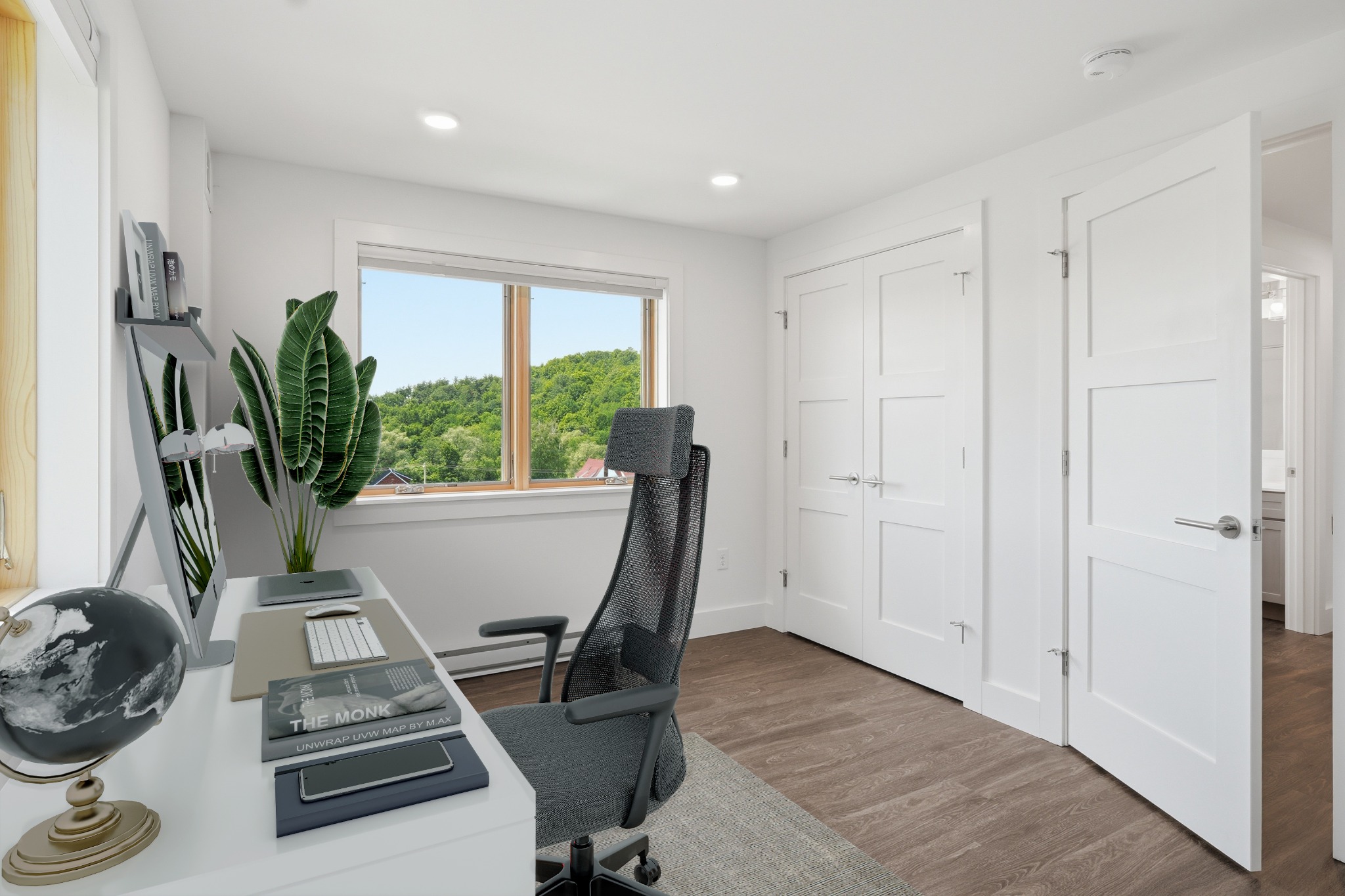 Home office with a desk, mesh task chair and large potted plant beside a window, with white paneled doors along the wall.